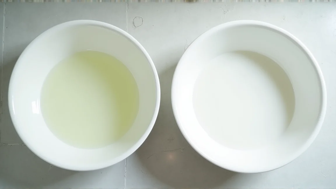 白い洗面器2つ。左は底まで透ける淡い黄緑色のお湯、右は底が見えない乳白色のお湯